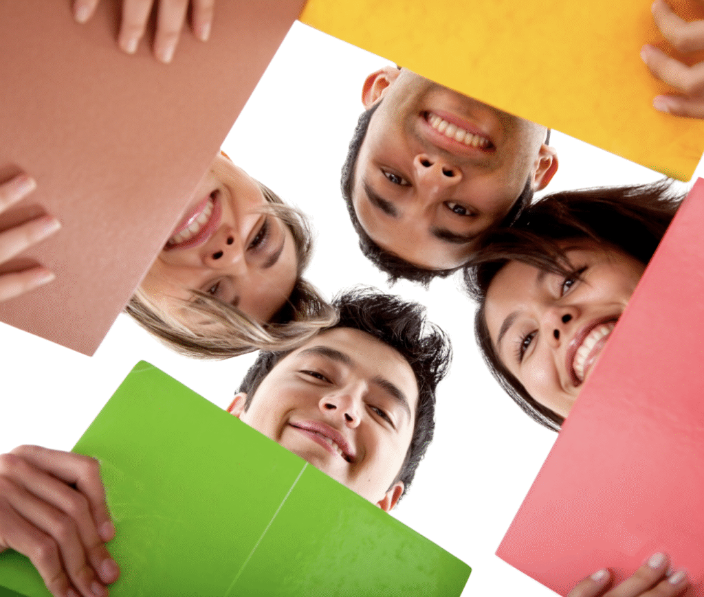 Group of smiling students looking down at colorful folders, symbolizing collaboration and creativity.